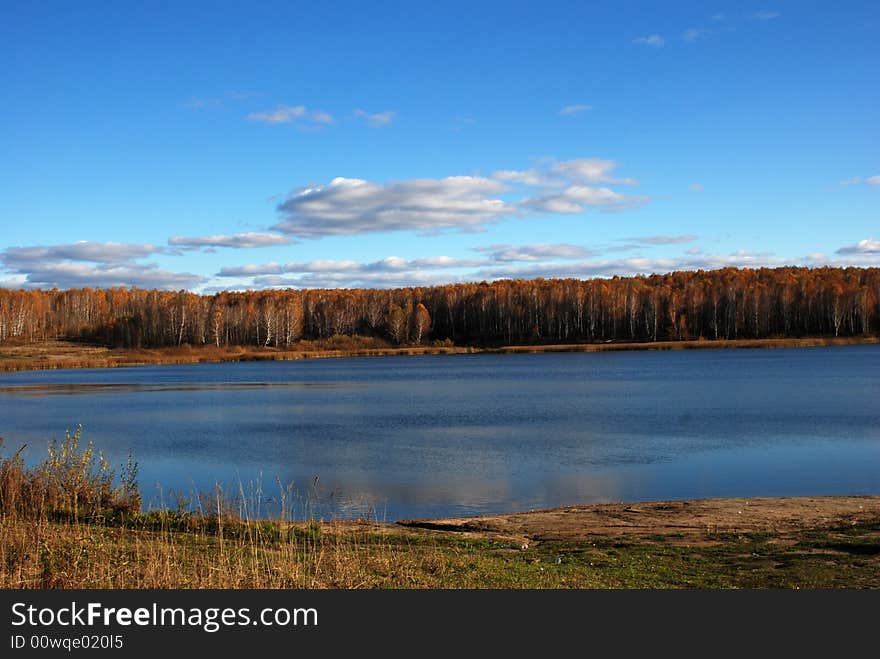 Small lake, autumn forest, clouds