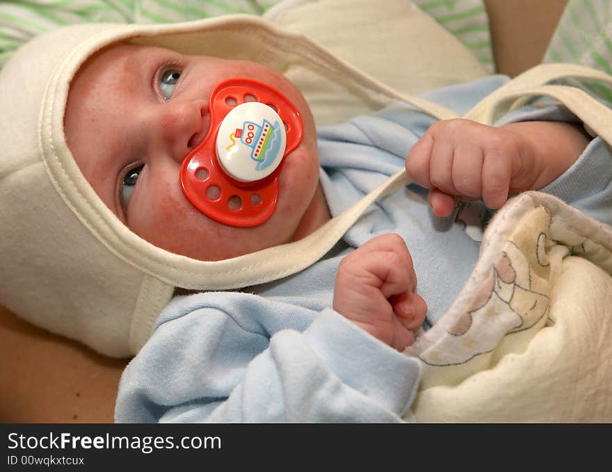 A new born baby with a cap and a pacifier. A new born baby with a cap and a pacifier