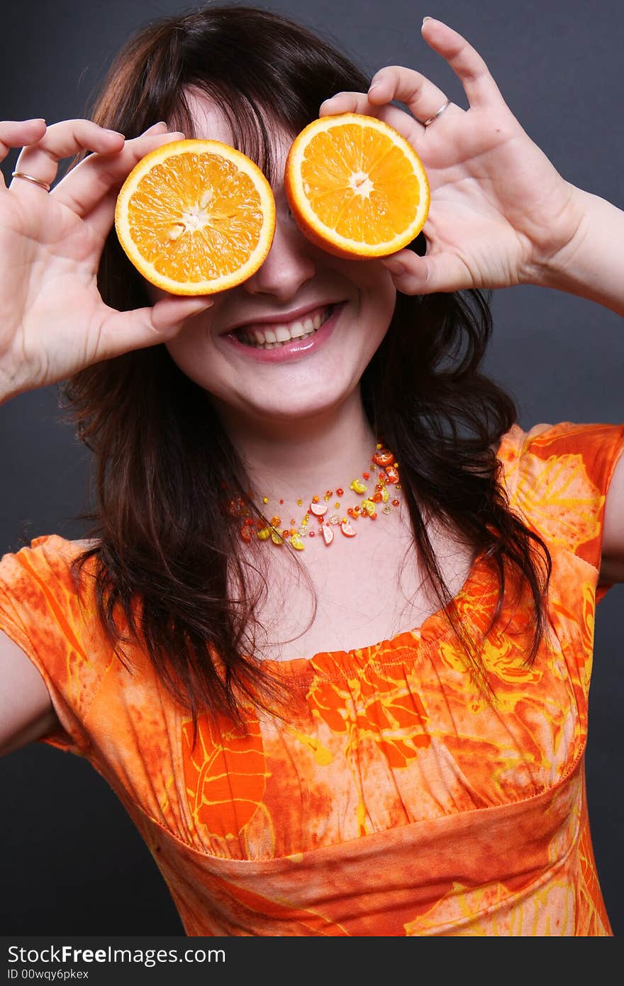 The positive smiling girl with an orange in hands. The positive smiling girl with an orange in hands