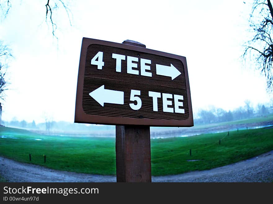 Tee sign directing carts on a golf course to the various holes.  Green visible behind sign. Tee sign directing carts on a golf course to the various holes.  Green visible behind sign.