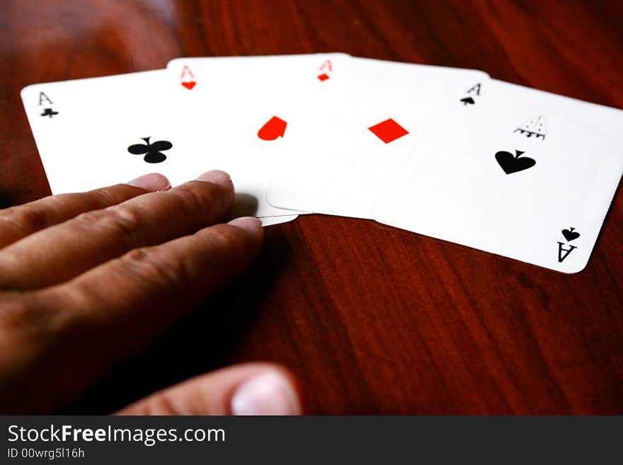 An image of four aces in a table with a person's hand. An image of four aces in a table with a person's hand.