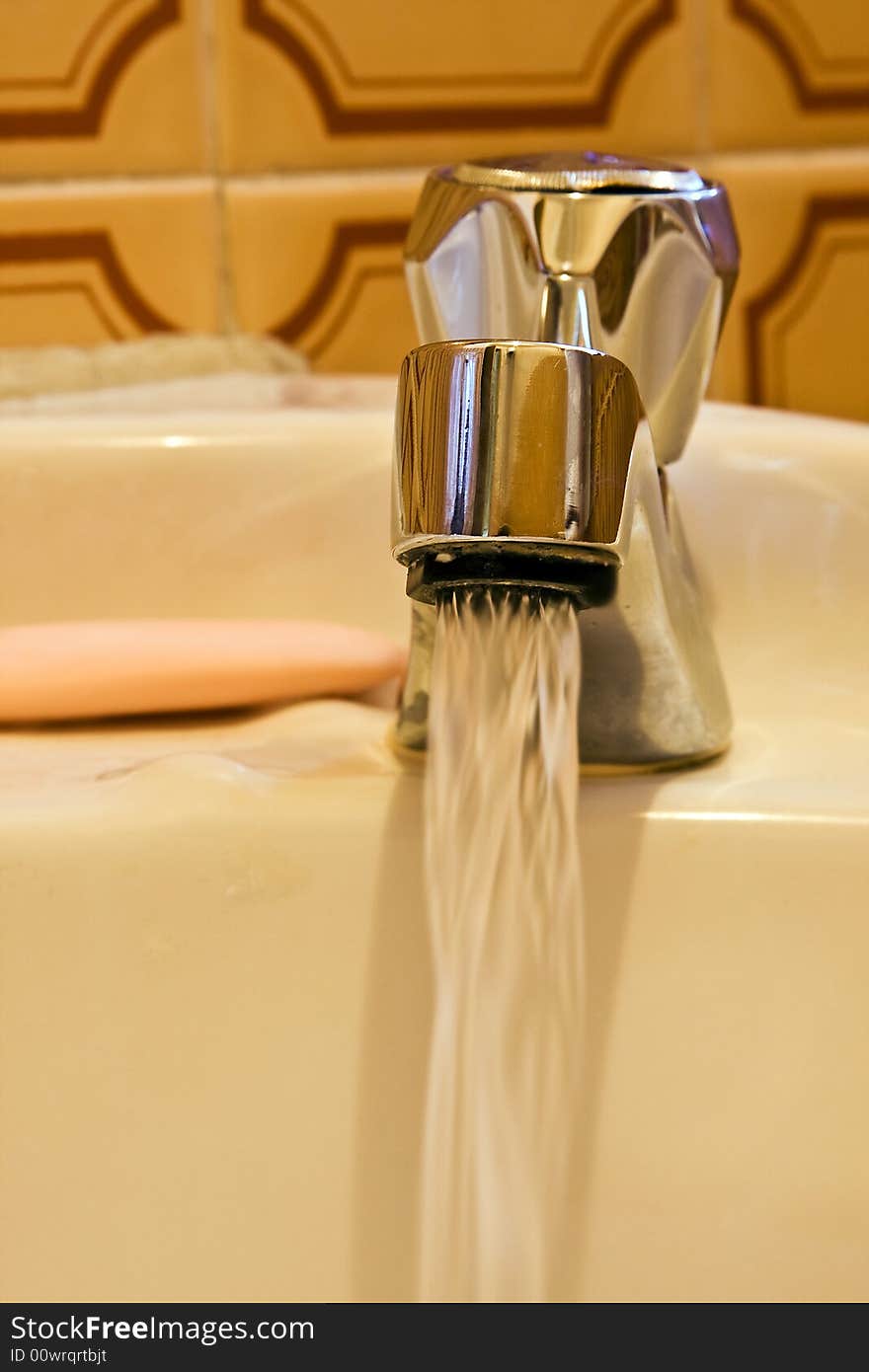 Hand washing basin with flowing water and soap.