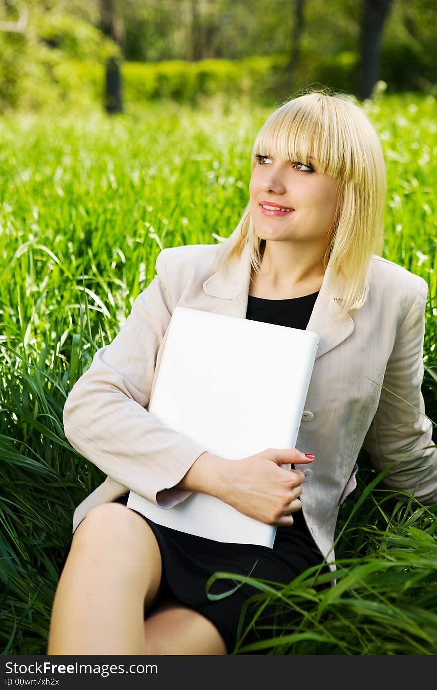 Smiling student with laptop on the grass. Smiling student with laptop on the grass