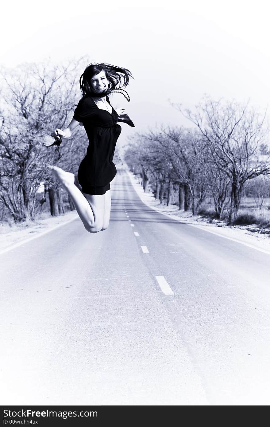 Happy girl jumping in the middle of the road