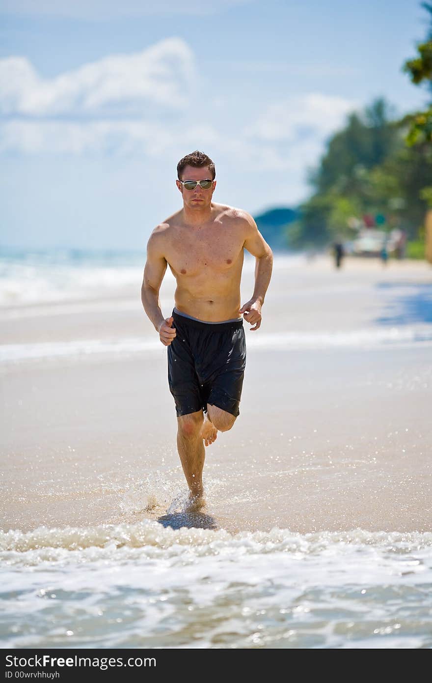 Caucasian man running on the beach with sunglasses. Caucasian man running on the beach with sunglasses