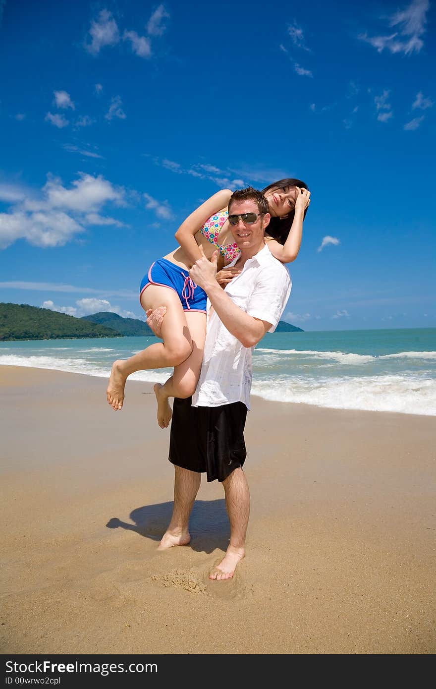 Young multiethnic couple enjoying themselves on a beautiful day at the beach. Young multiethnic couple enjoying themselves on a beautiful day at the beach