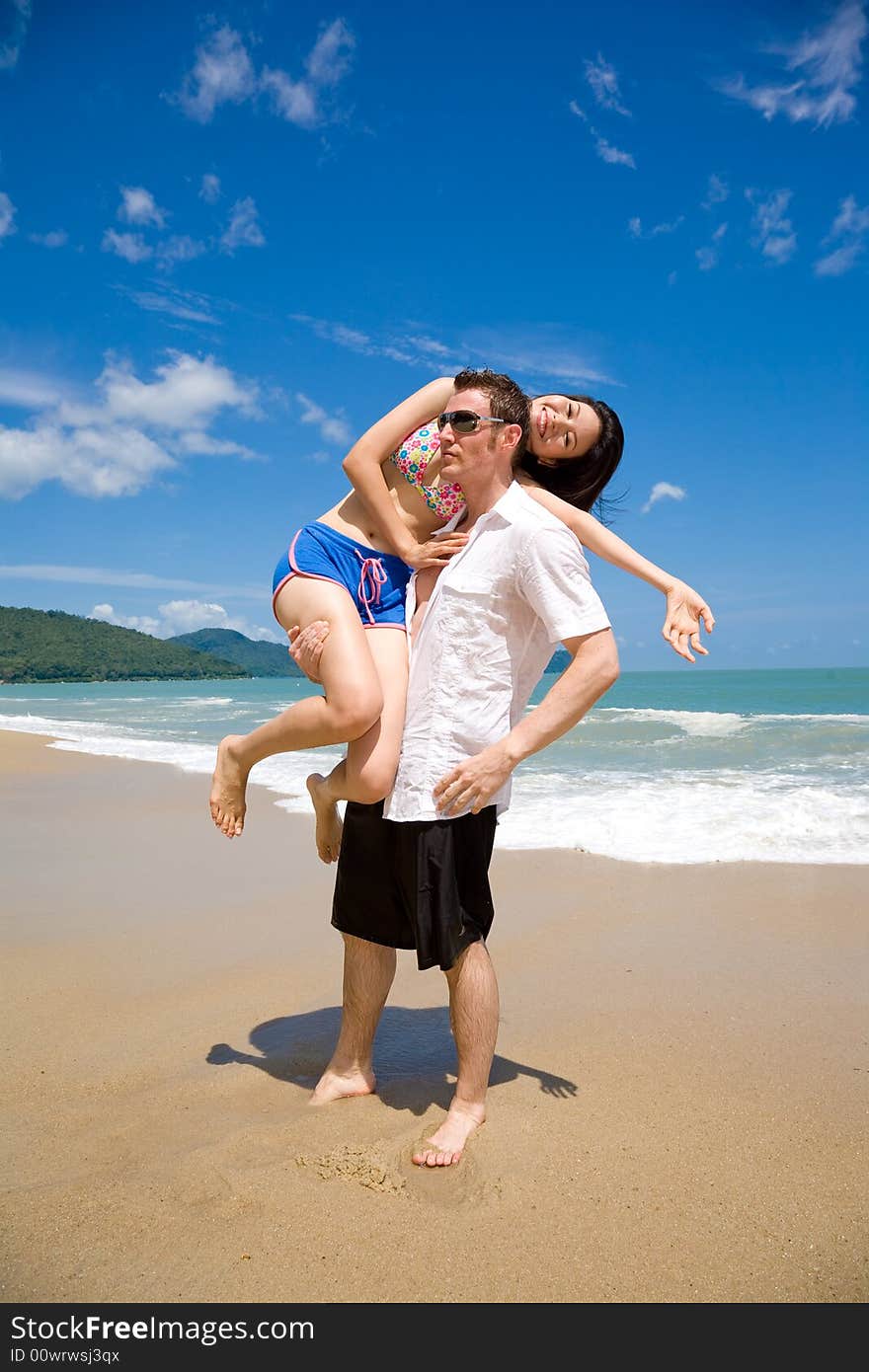 Young multiethnic couple enjoying themselves on a beautiful day at the beach. Young multiethnic couple enjoying themselves on a beautiful day at the beach