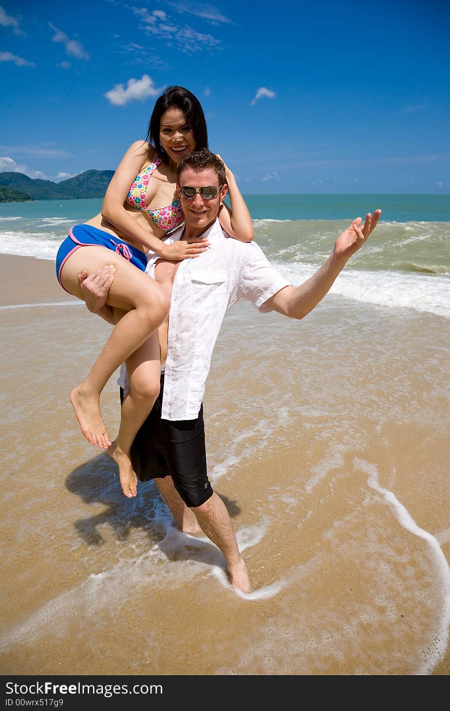 Young multiethnic couple enjoying themselves on a beautiful day at the beach. Young multiethnic couple enjoying themselves on a beautiful day at the beach