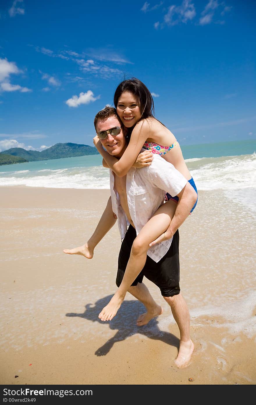 Caucasian hunk carrying a gorgeous asian woman on his back having lots of fun. Caucasian hunk carrying a gorgeous asian woman on his back having lots of fun