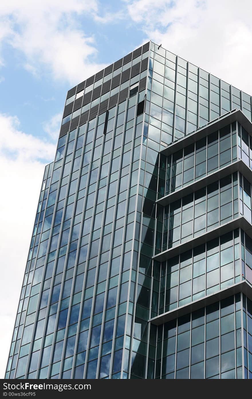 Modern office building with reflection of cloudy sky. Vertical perspective.