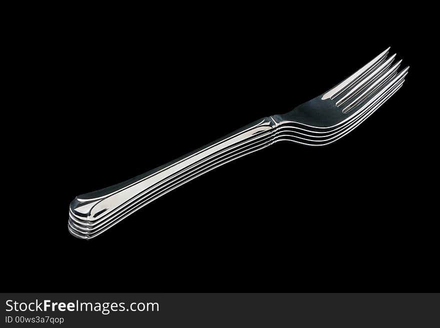 A pile of five silver forks, isolated on black