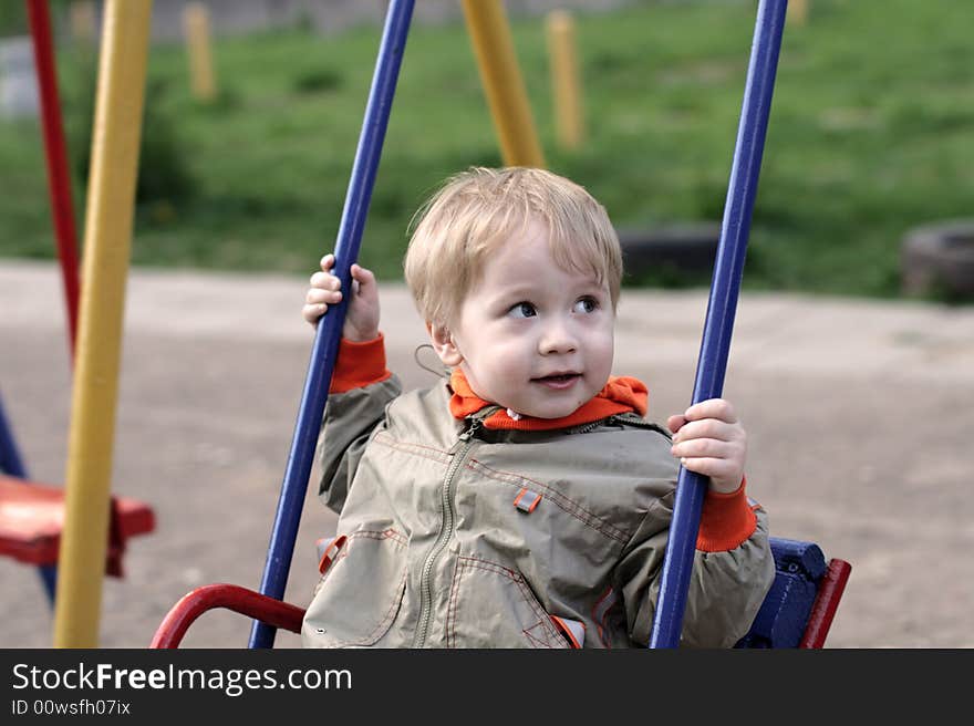 The boy on the swing in the playground. The boy on the swing in the playground