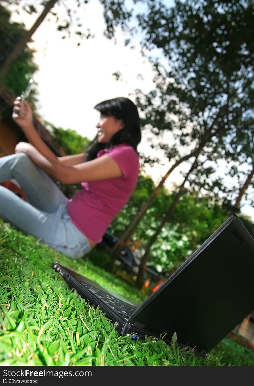 laptop with girl holding cellphone at background in nature. laptop with girl holding cellphone at background in nature