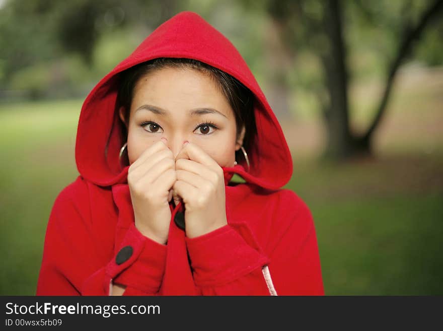 Young Asian girl in a bright red coat with hood. Young Asian girl in a bright red coat with hood