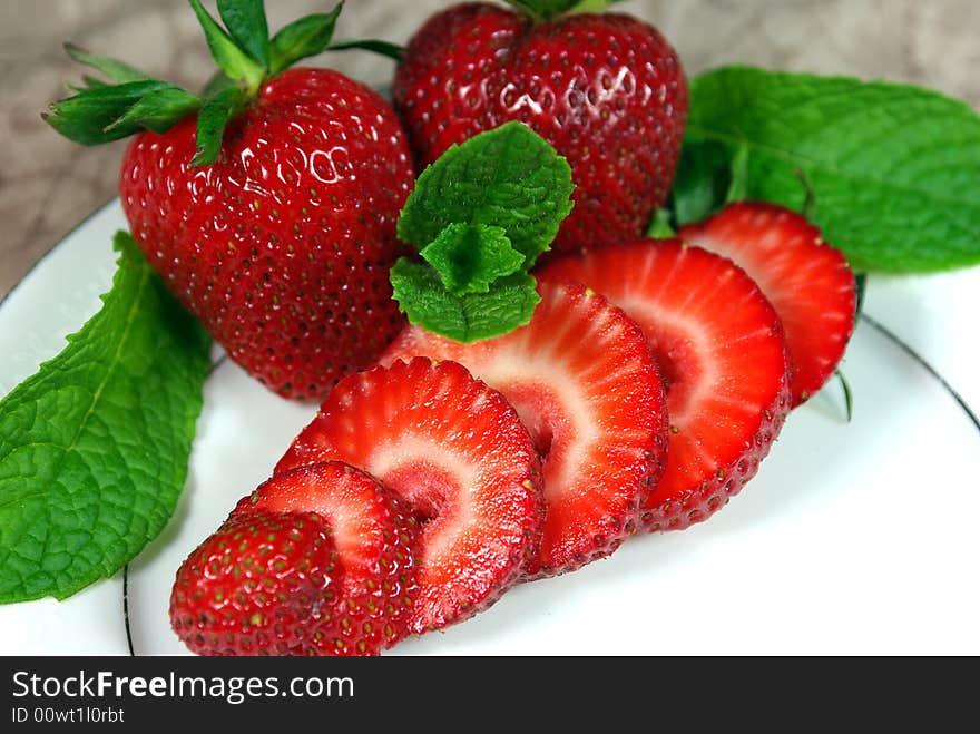 Fresh whole and sliced Strawberries on a white plate. Fresh whole and sliced Strawberries on a white plate.