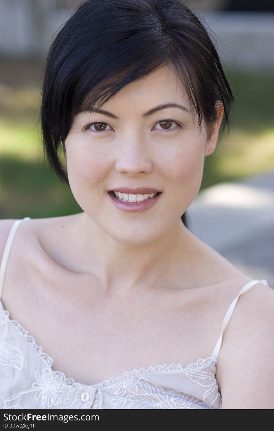 A beautiful woman sitting, wearing a white camisole in the spring outdoors. A beautiful woman sitting, wearing a white camisole in the spring outdoors.