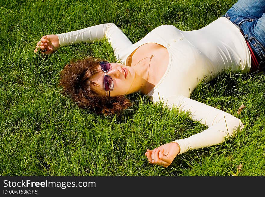 Looking to camera beauty girl with big breast is smiling and relaxing on the grass. Looking to camera beauty girl with big breast is smiling and relaxing on the grass