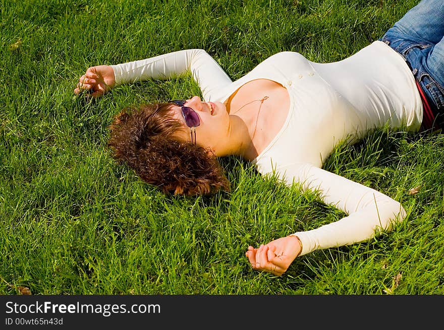 Beauty girl with big breast is smiling and relaxing on the grass. Beauty girl with big breast is smiling and relaxing on the grass