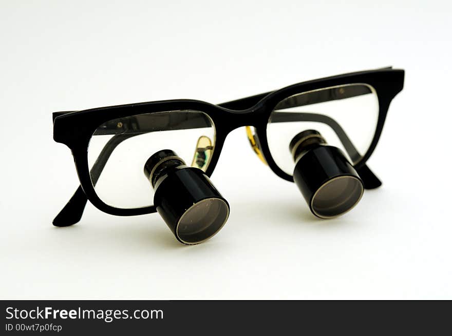 A pair of magnifying glasses for surgical use with the earpieces folded closed. A pair of magnifying glasses for surgical use with the earpieces folded closed.