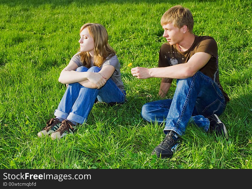 Young man giving dandelion to young woman to make her not to be offended. Young man giving dandelion to young woman to make her not to be offended