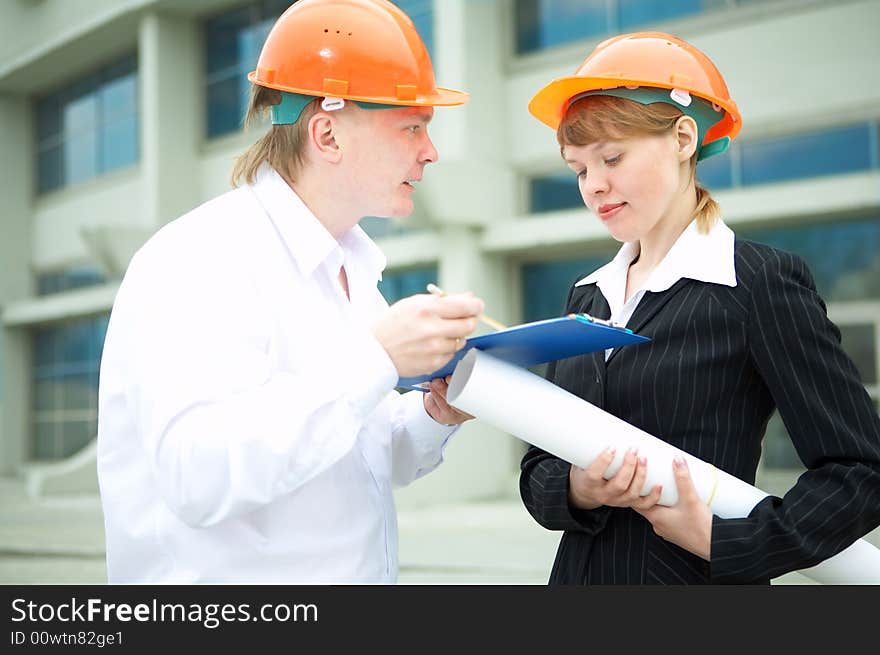 Architects man and woman protective helmet standing in front of a building