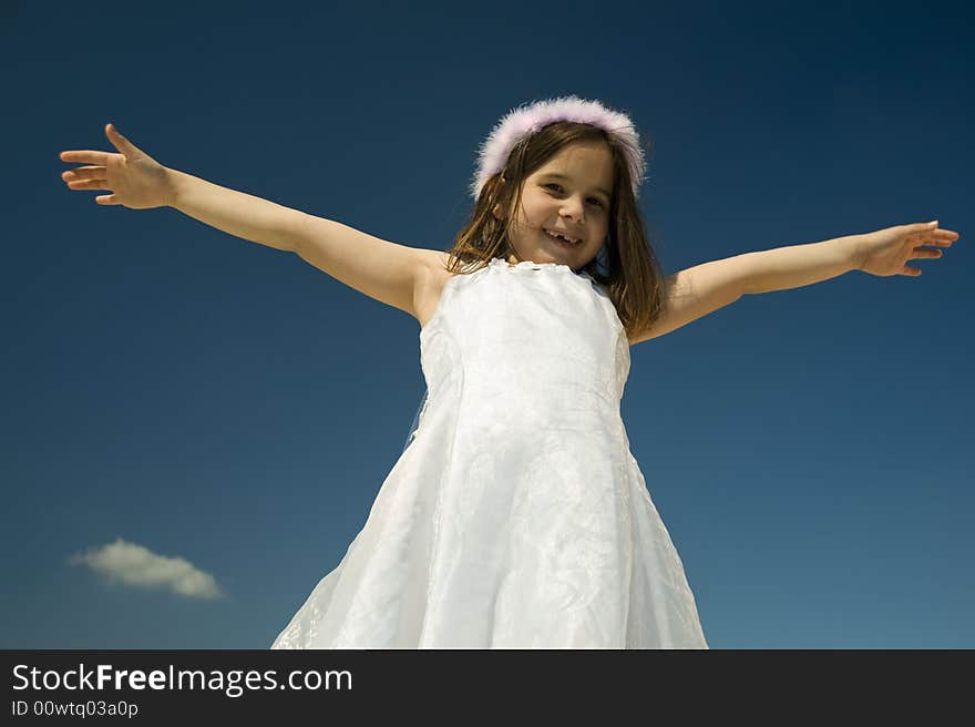 Young girl with spreads arms against blue sky. Young girl with spreads arms against blue sky