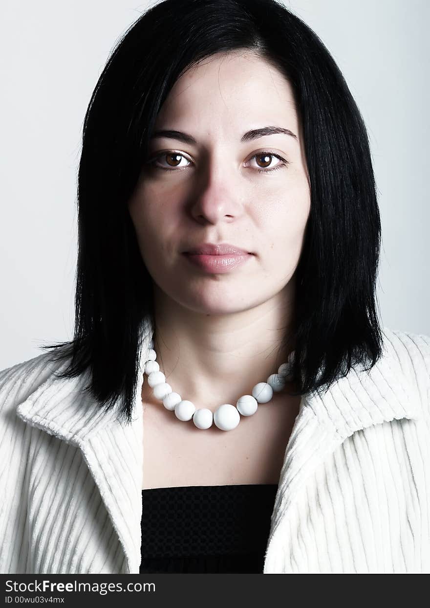 A high-key portrait about a pretty trendy lady with black hair who is looking ahead and she has an attractive look. She is wearing a white coat, a black dress and a white necklace. A high-key portrait about a pretty trendy lady with black hair who is looking ahead and she has an attractive look. She is wearing a white coat, a black dress and a white necklace.