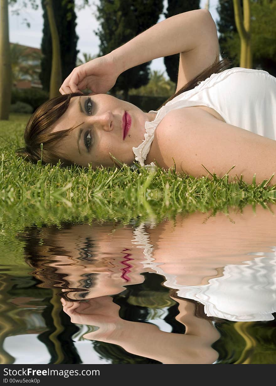 Portrait of a woman lying on the grass with water reflection. Portrait of a woman lying on the grass with water reflection