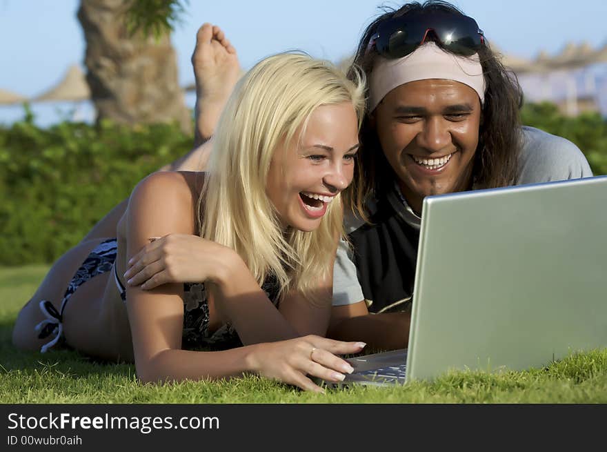 Young multi-ethnic couple lay on grass with laptop. Young multi-ethnic couple lay on grass with laptop.