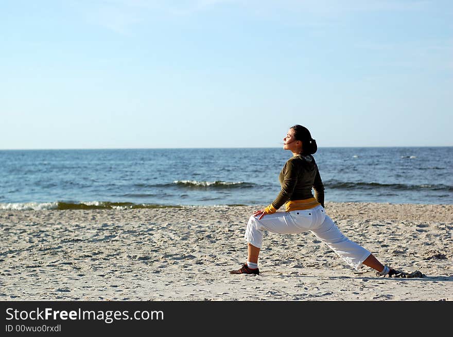 Attractive brunette woman doing exercise on the beach. Attractive brunette woman doing exercise on the beach