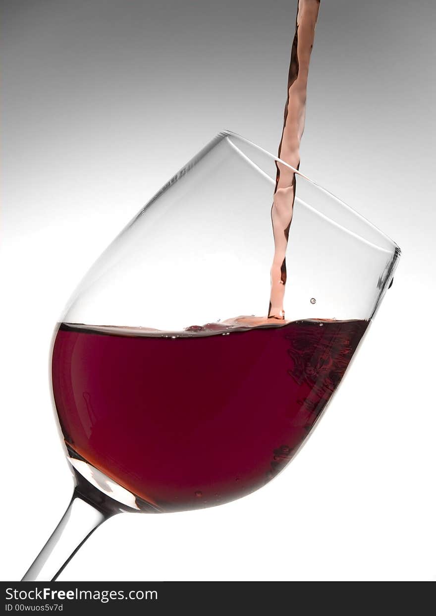 A malbec glass pouring with red wine. A malbec glass pouring with red wine