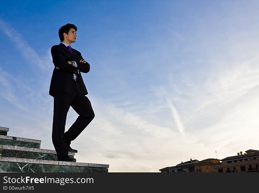 Businessman posing on stairs against blue sky. Businessman posing on stairs against blue sky.