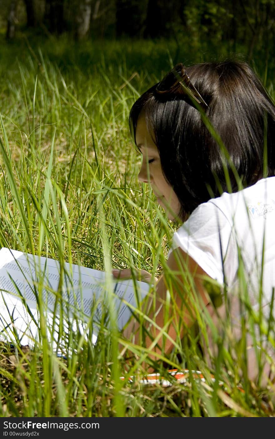 Pretty young girl reading on the grass