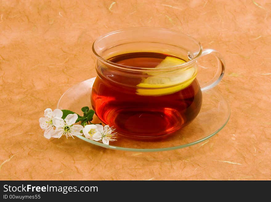 Tea with lemon on glass cup on an orange background.