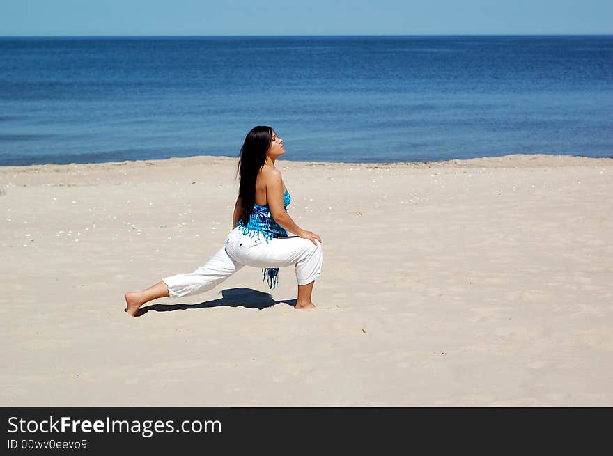 Attractive brunette woman doing exercise on the beach. Attractive brunette woman doing exercise on the beach