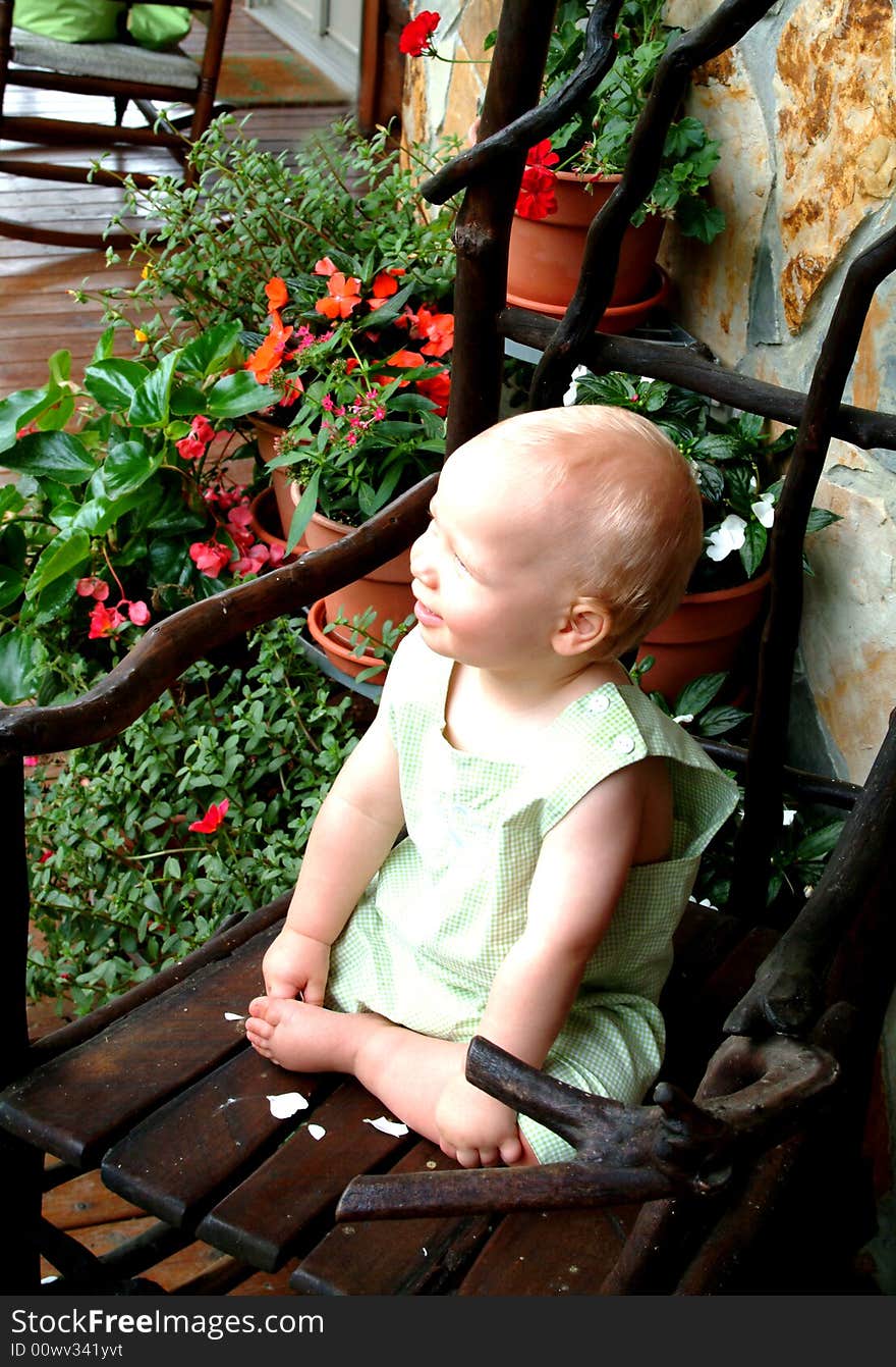 Baby boy on willow rocking chair on front porch of family home. Baby boy on willow rocking chair on front porch of family home