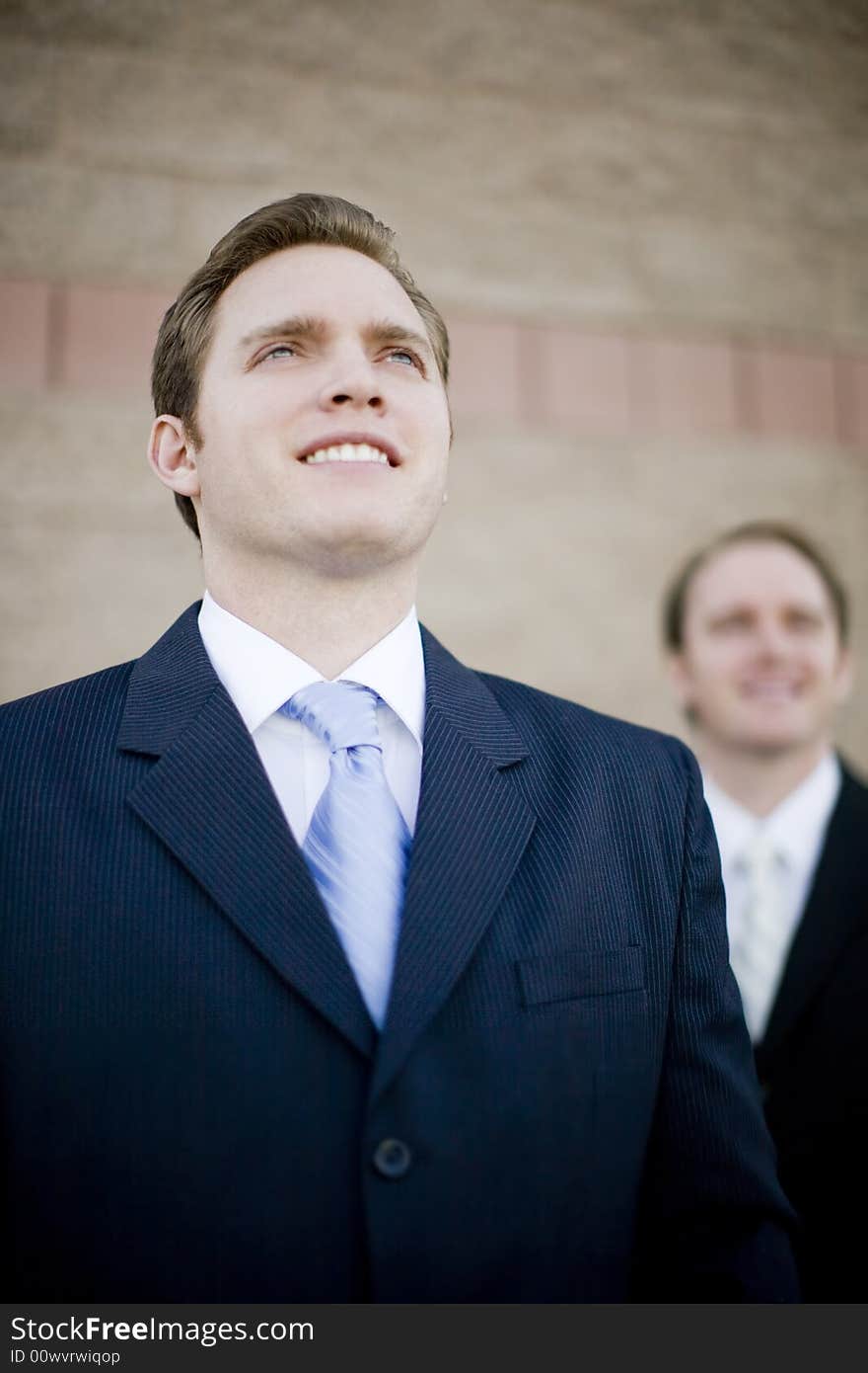 Two Businessman standing smiling and wearing suits looking forward. Two Businessman standing smiling and wearing suits looking forward