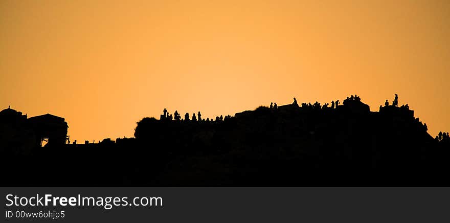 People silhouetted against the sunset along the cliff Santorini