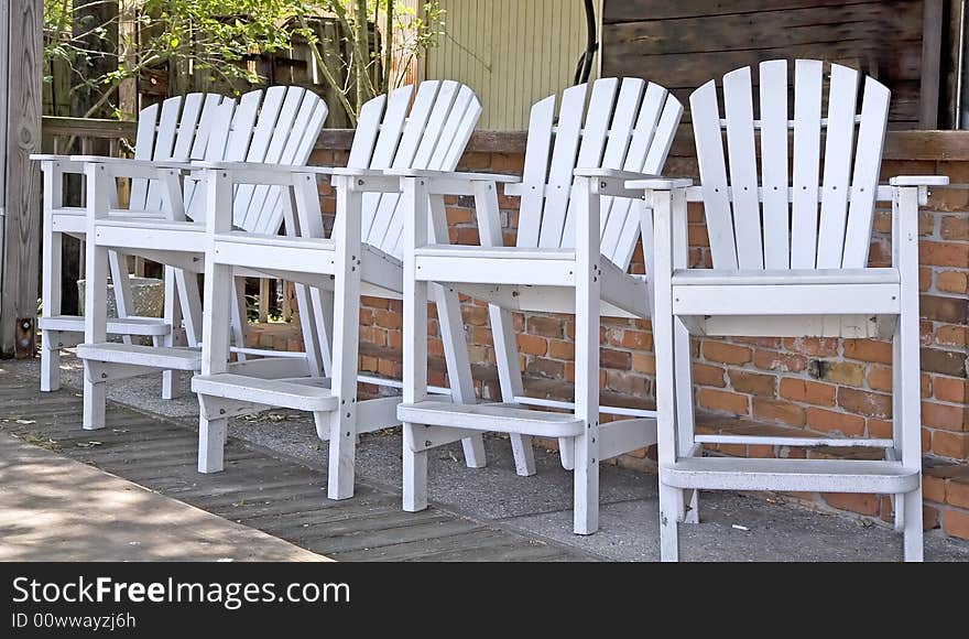 Five high adirondack white wooden chairs at an outside bar. Five high adirondack white wooden chairs at an outside bar