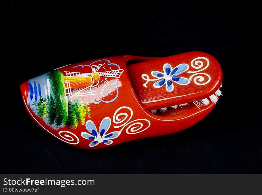 Red shoe brush with natural wild bristles and wooden grip isolated on black background