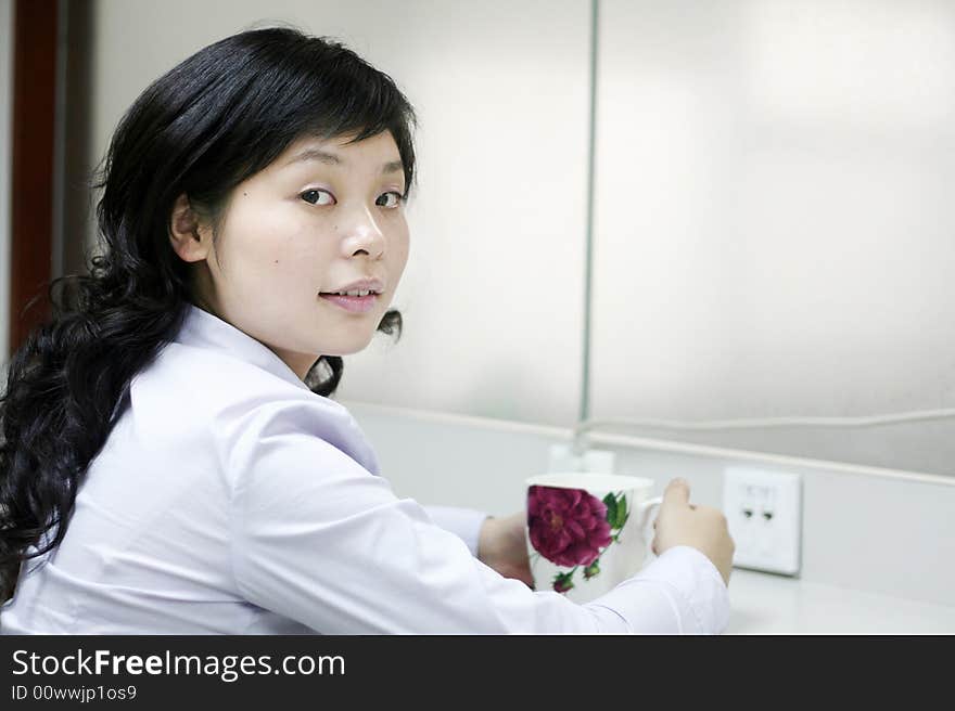 Young women having a cup of drinking in office. Young women having a cup of drinking in office