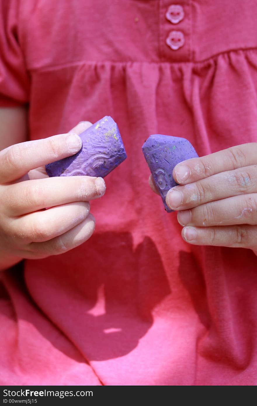 Girl with colorful pink shirt holding purple sidewalk chalk in the summer. Girl with colorful pink shirt holding purple sidewalk chalk in the summer