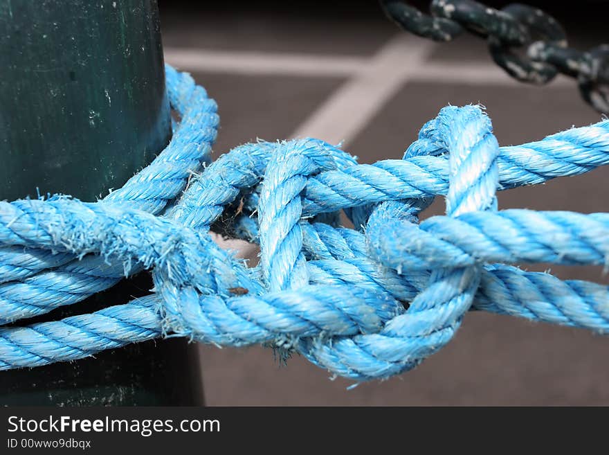 Detail of a blue rope, tied to a pole, at the dock