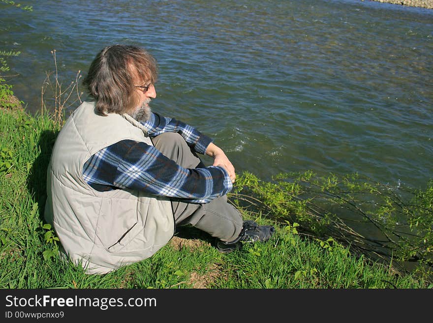 Man sitting by the river and watching water flows. Man sitting by the river and watching water flows