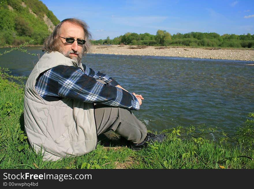 Man relaxing by the river on a spring sunny warm day. Man relaxing by the river on a spring sunny warm day