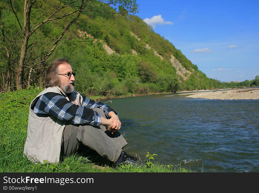 Man relaxing by the river on a spring sunny warm day. Man relaxing by the river on a spring sunny warm day