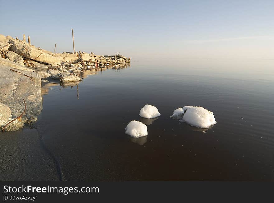 Chunks of white foam floating in the murky, polluted brine of the Salton Sea, California. Chunks of white foam floating in the murky, polluted brine of the Salton Sea, California.