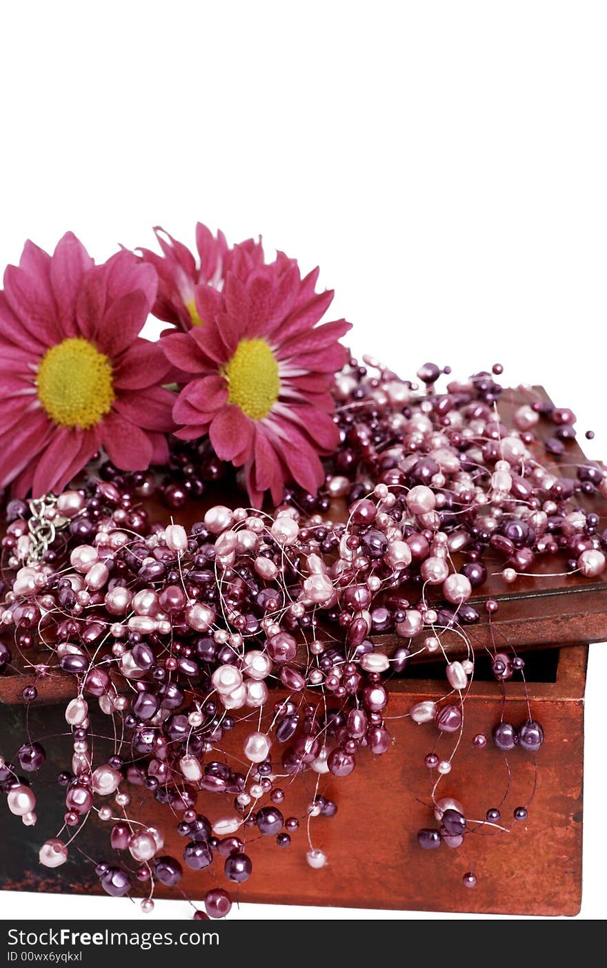 Fashionable fake pink pearls with bright pink flowers on aged dark wooden box, isolated on white background. Fashionable fake pink pearls with bright pink flowers on aged dark wooden box, isolated on white background