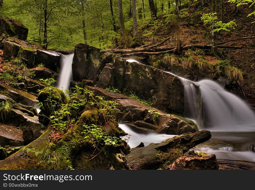 Mountain river in the forest of mountains with a waterfall