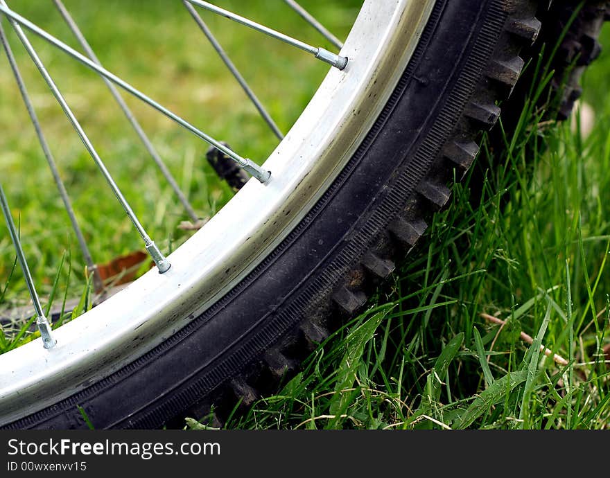 Close up view of a parked bicycle tire on green grass. Close up view of a parked bicycle tire on green grass